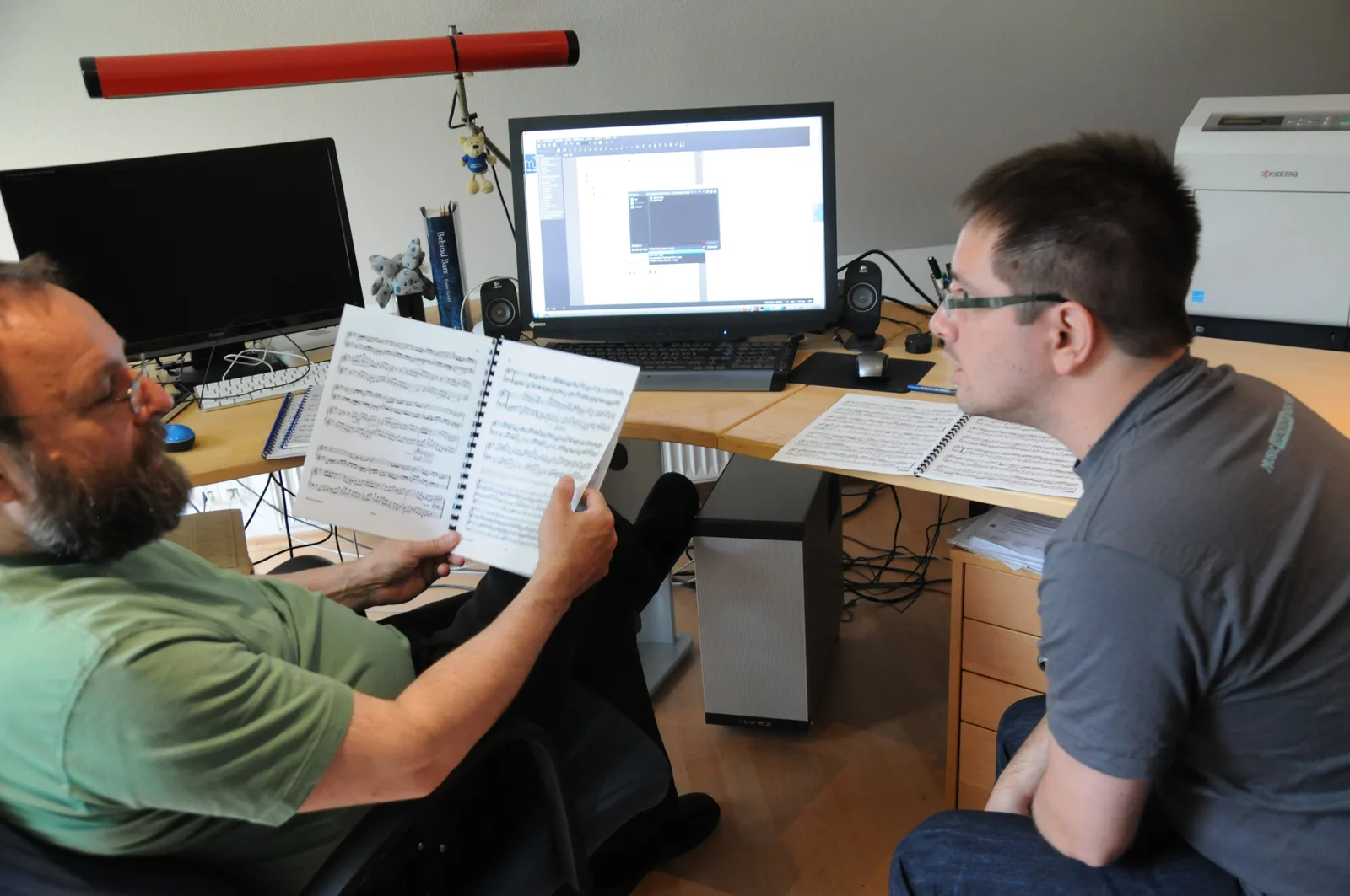 Two developers at a desk discussing new software features in front of a workstation