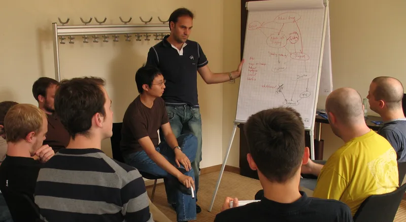 Group of software engineers gathered around laptops at a table, working on designs together