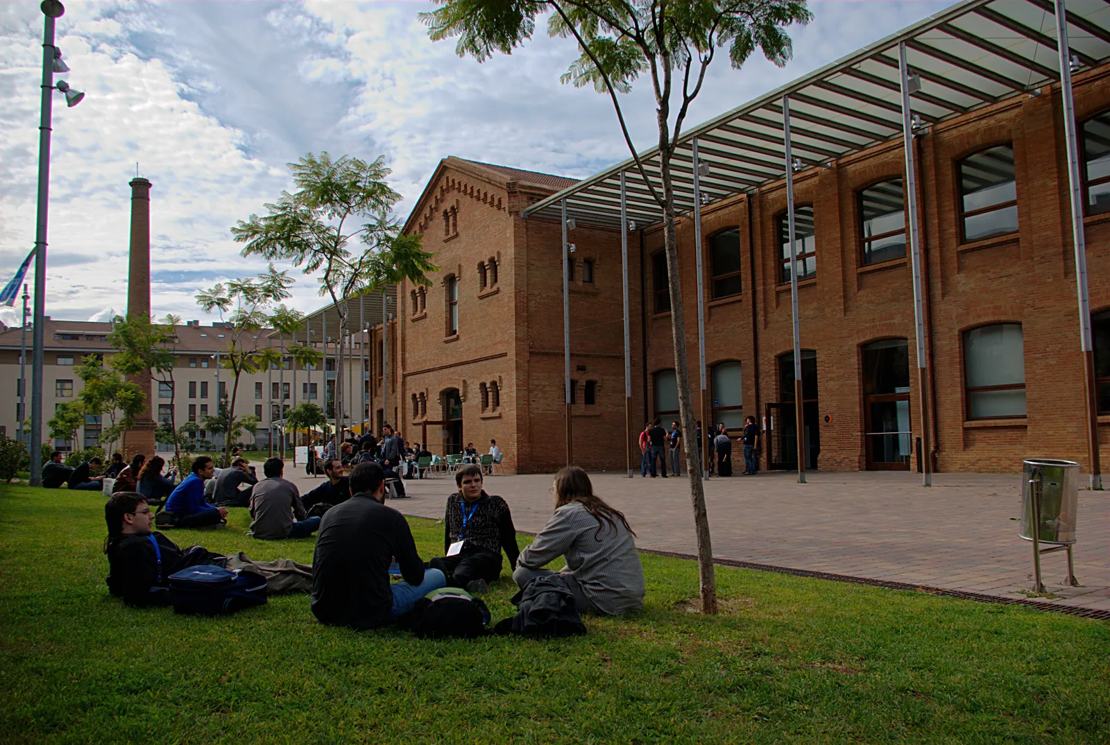 Conference attendees sitting on the grass outside a brick building during a PHP conference break