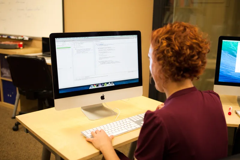Developer typing at a desktop computer showing an editor with code and passing unit tests