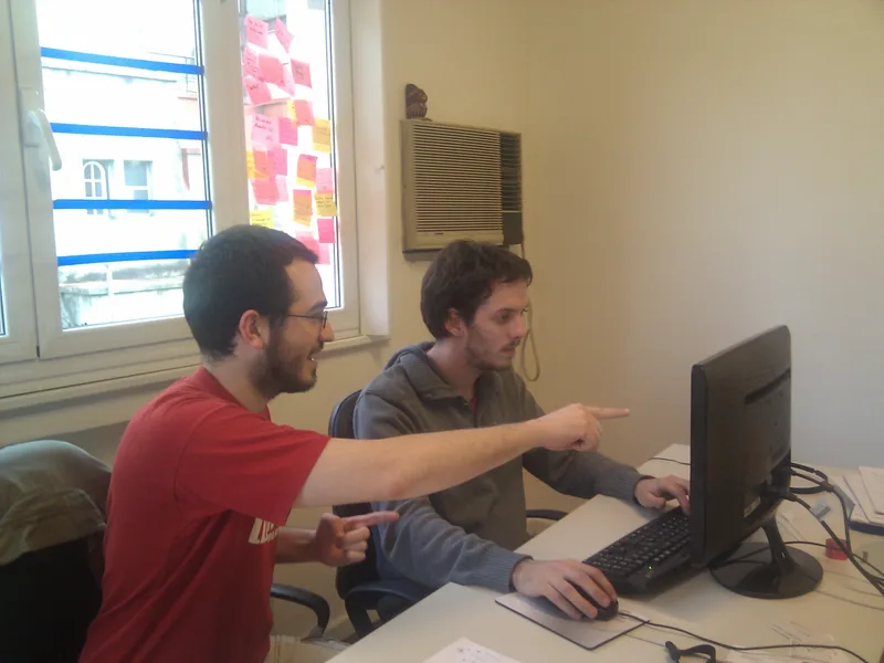 Two programmers sharing one workstation and discussing code together