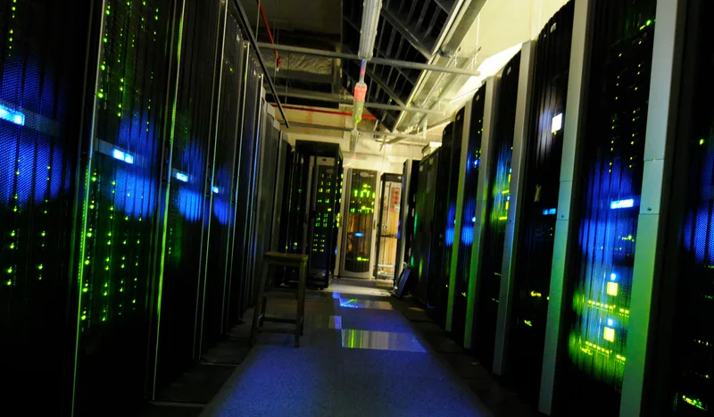 Server room with rows of black equipment racks and a raised floor