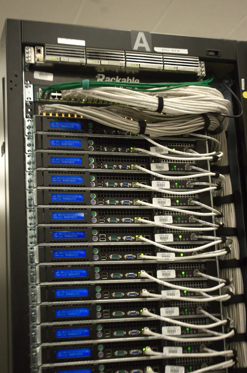 Close-up of the back of a server rack with white Ethernet cables and small blue LED displays