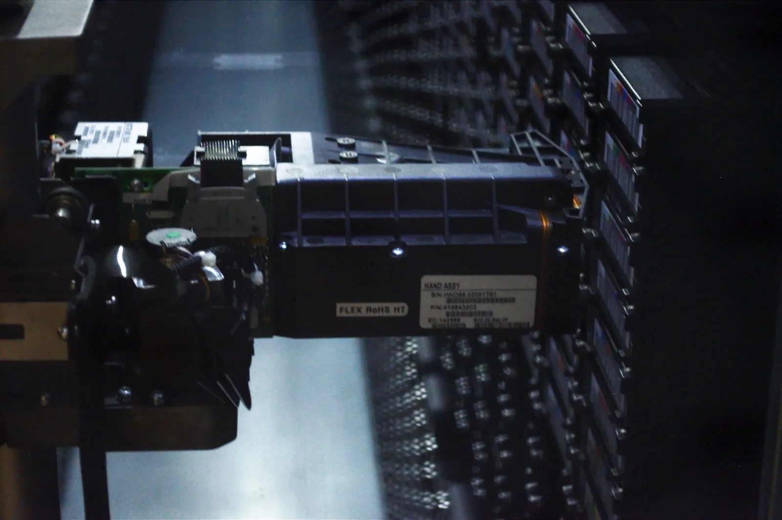 Close-up of a robotic arm inside a tape library picking a cartridge from a storage slot