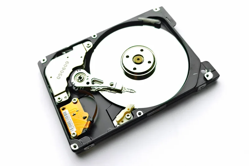 Mirror-like platter of a 2.5-inch hard disk drive photographed against a dark background