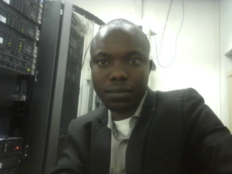 Engineer working at a laptop beside server racks in a dimly lit server room at night