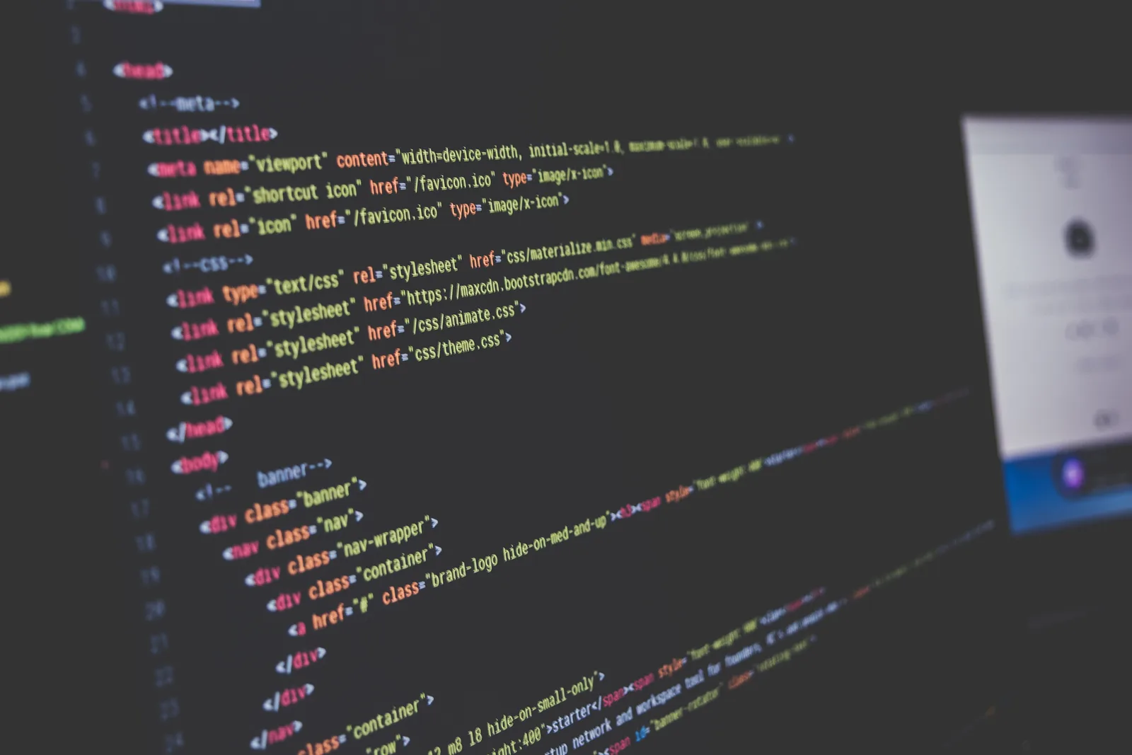 HTML head and body markup with syntax highlighting in a dark code editor on a monitor