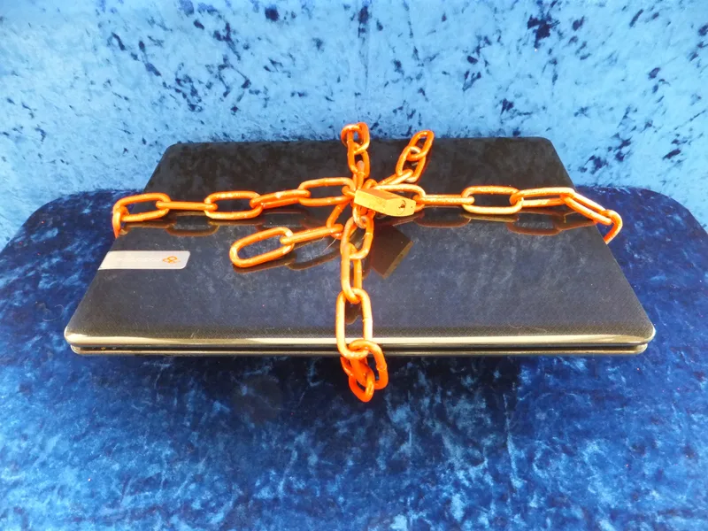 Laptop computer secured to a desk with a metal chain and padlock