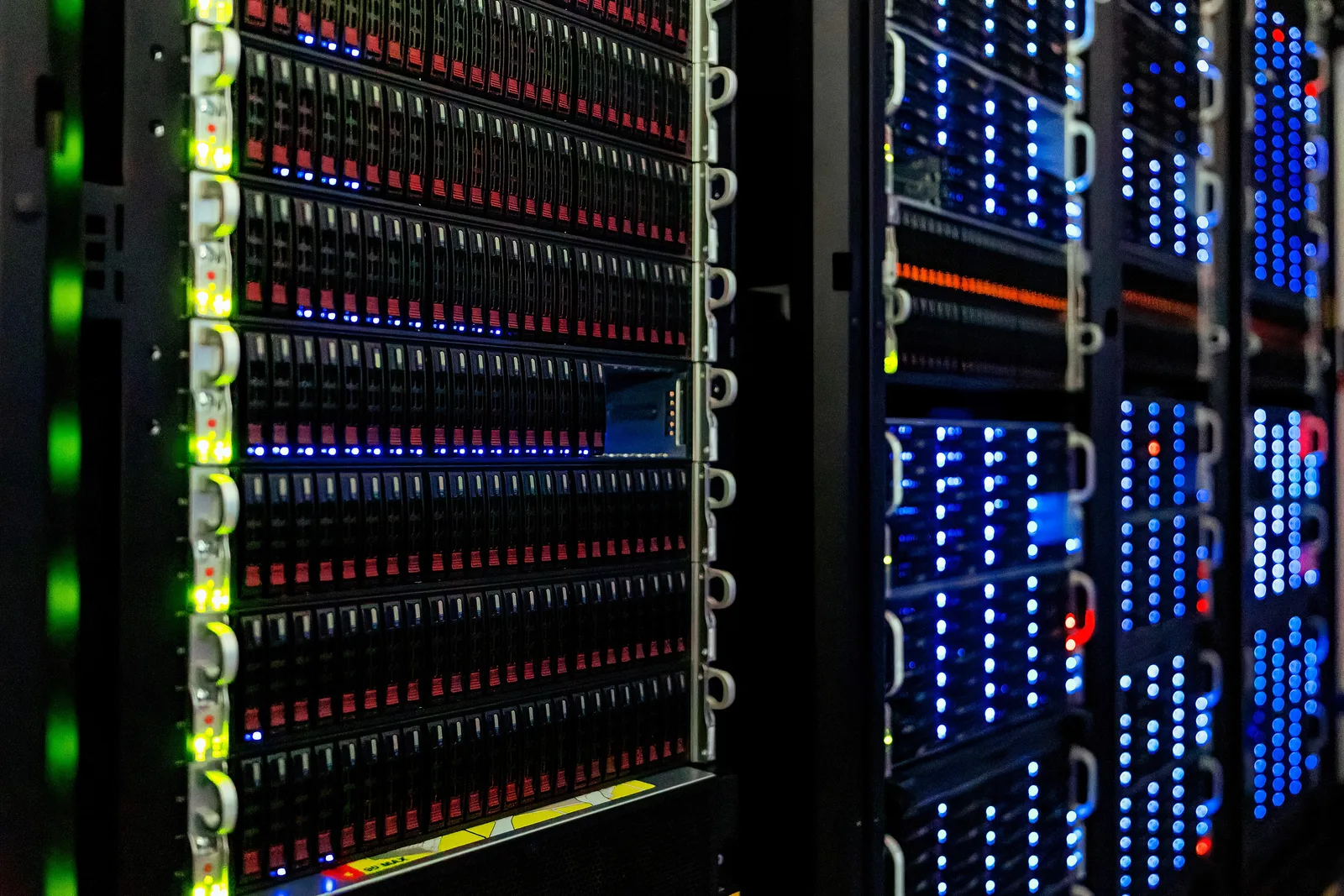 Close-up of server racks with rows of drive bays lit by green, red and blue status lights