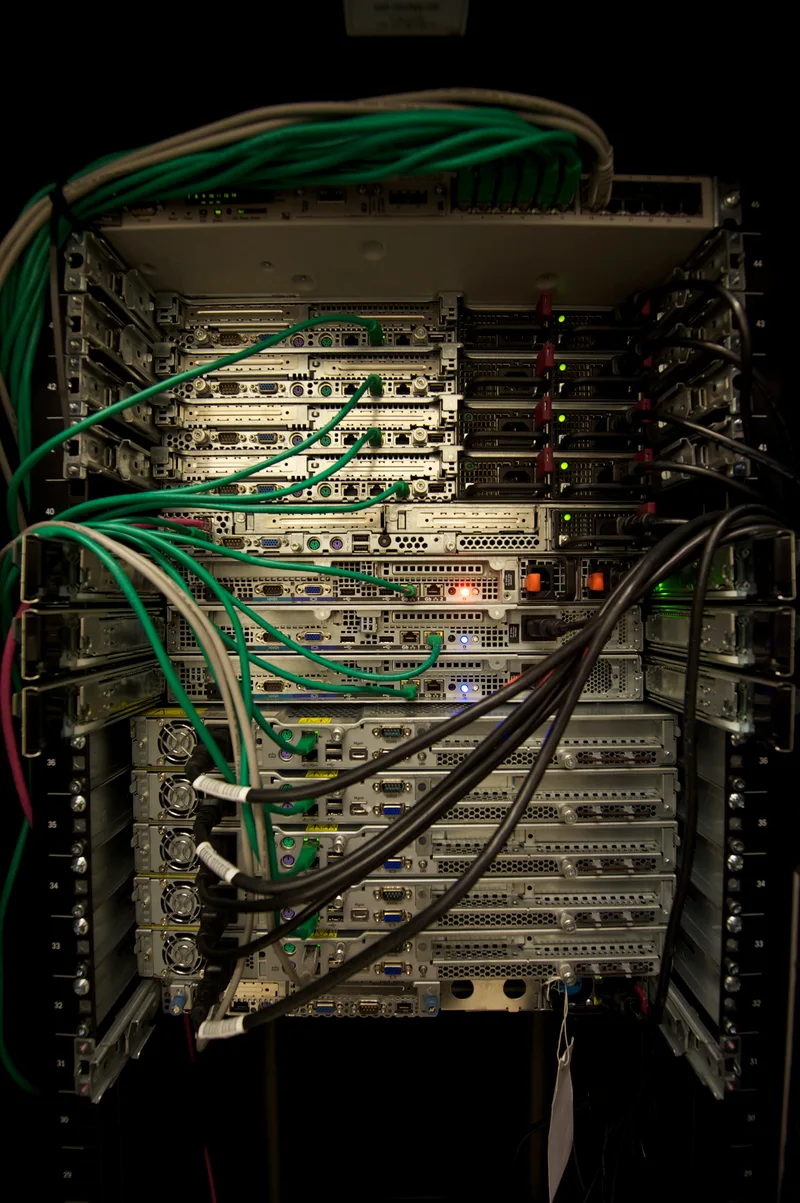 Rack of servers with green and black network cables connected to the front panels