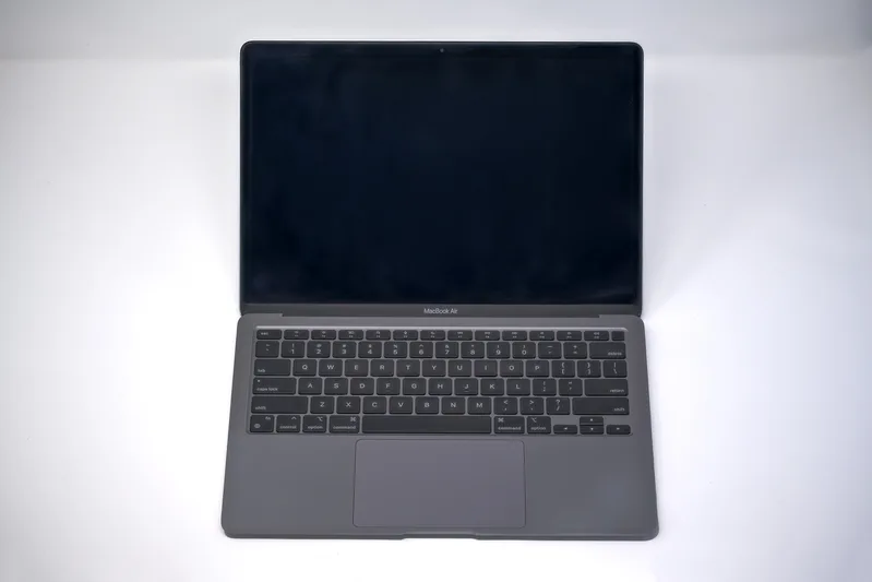 Open space-grey MacBook Air with Apple silicon on a plain white background
