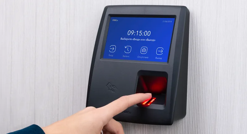 Finger pressed on the fingerprint sensor of a wall-mounted access terminal with a touch screen