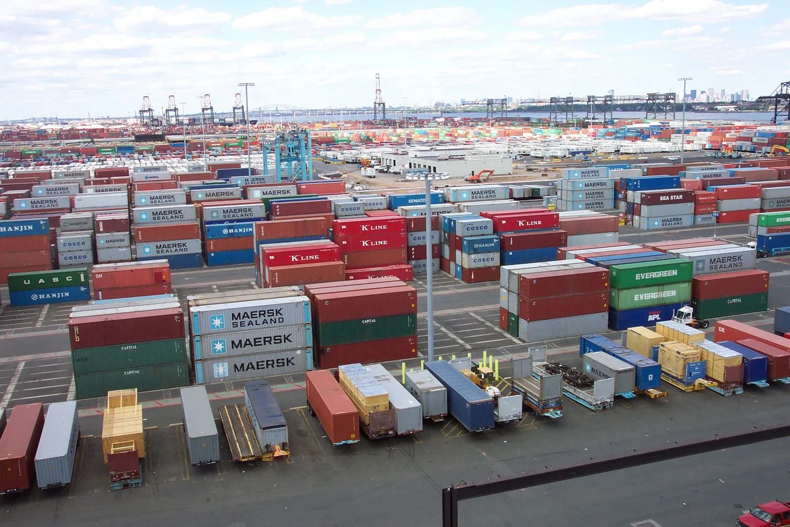 Wide view of thousands of shipping containers stacked in rows at the Port Elizabeth terminal in New Jersey, with cranes in the distance