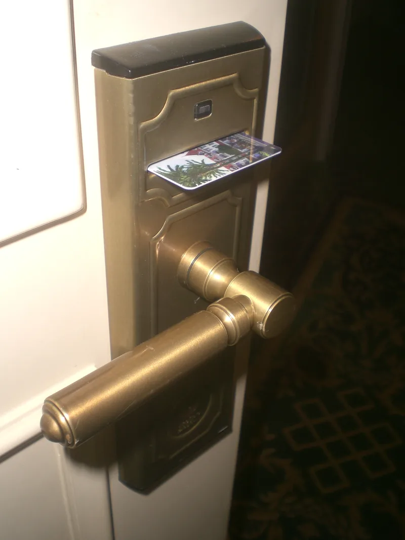 Hotel room door handle with an electronic lock and a key card inserted in its reader slot