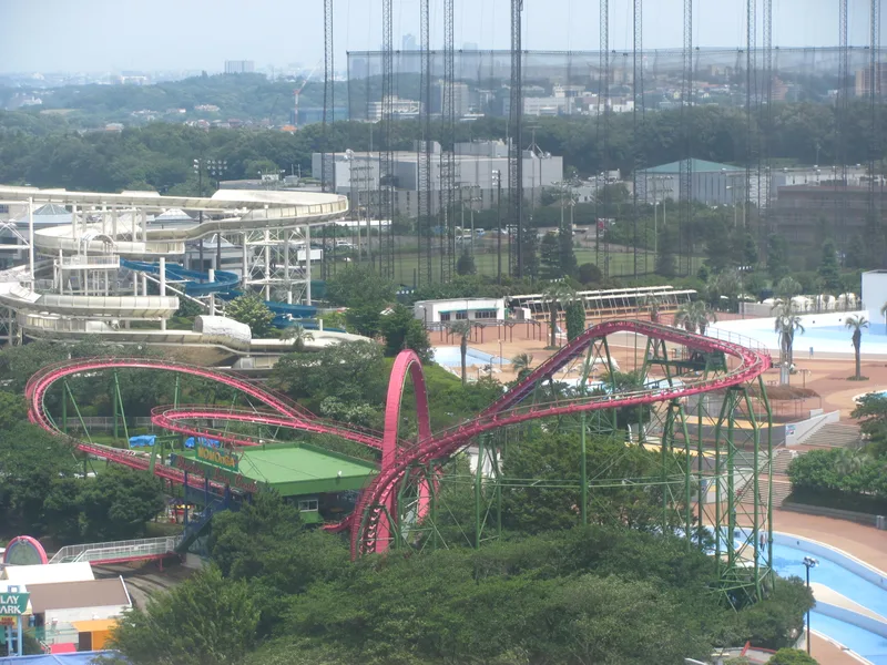 A pink steel roller coaster with a vertical loop and helix on green supports at the Yomiuriland amusement park