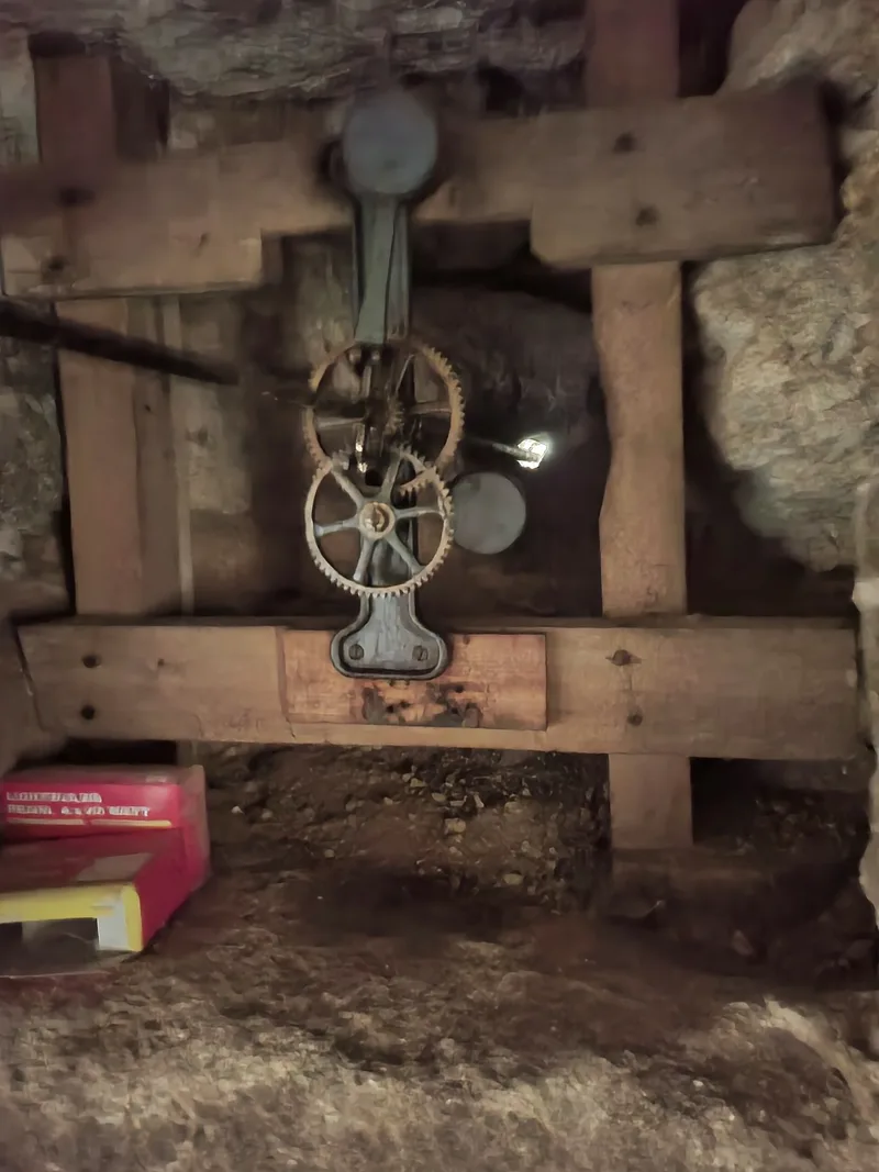 Two interlocking iron gears of an old church tower clock mechanism mounted on a wooden frame