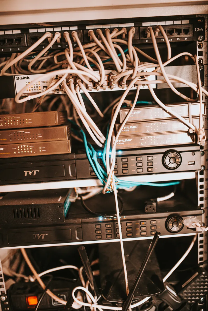 Server rack with network switches and recorders connected by bundles of white and blue cables