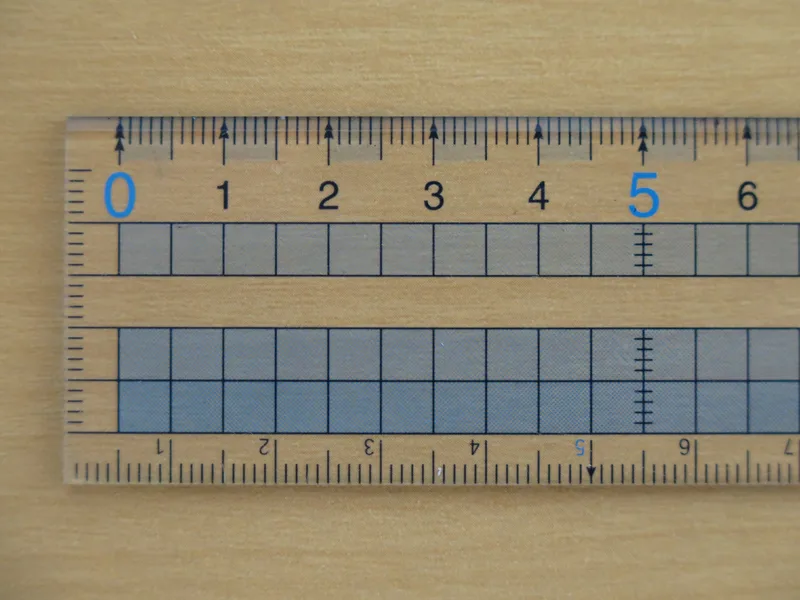 Transparent ruler with centimetre markings lying on a light wooden table
