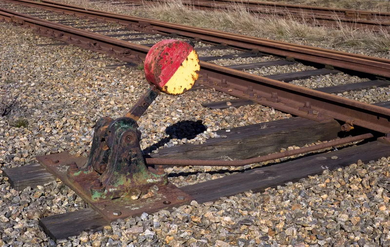A manual railway switch lever with a red and yellow disc beside a track in Grötö, Lysekil, Sweden
