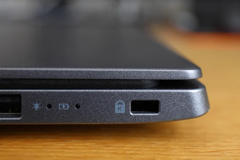 Close-up of the edge of a grey laptop showing a security lock slot beside status lights