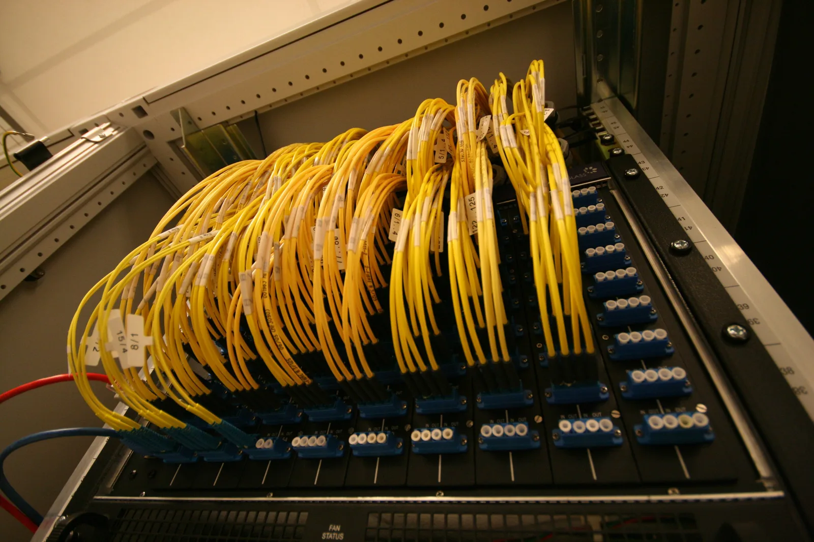 Dozens of labelled yellow fibre-optic patch cables plugged into an optical patch panel at the AMS-IX internet exchange in Amsterdam