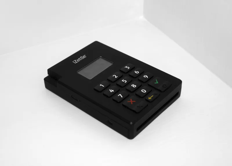 Small black iZettle card payment terminal with a numeric keypad on a white shelf