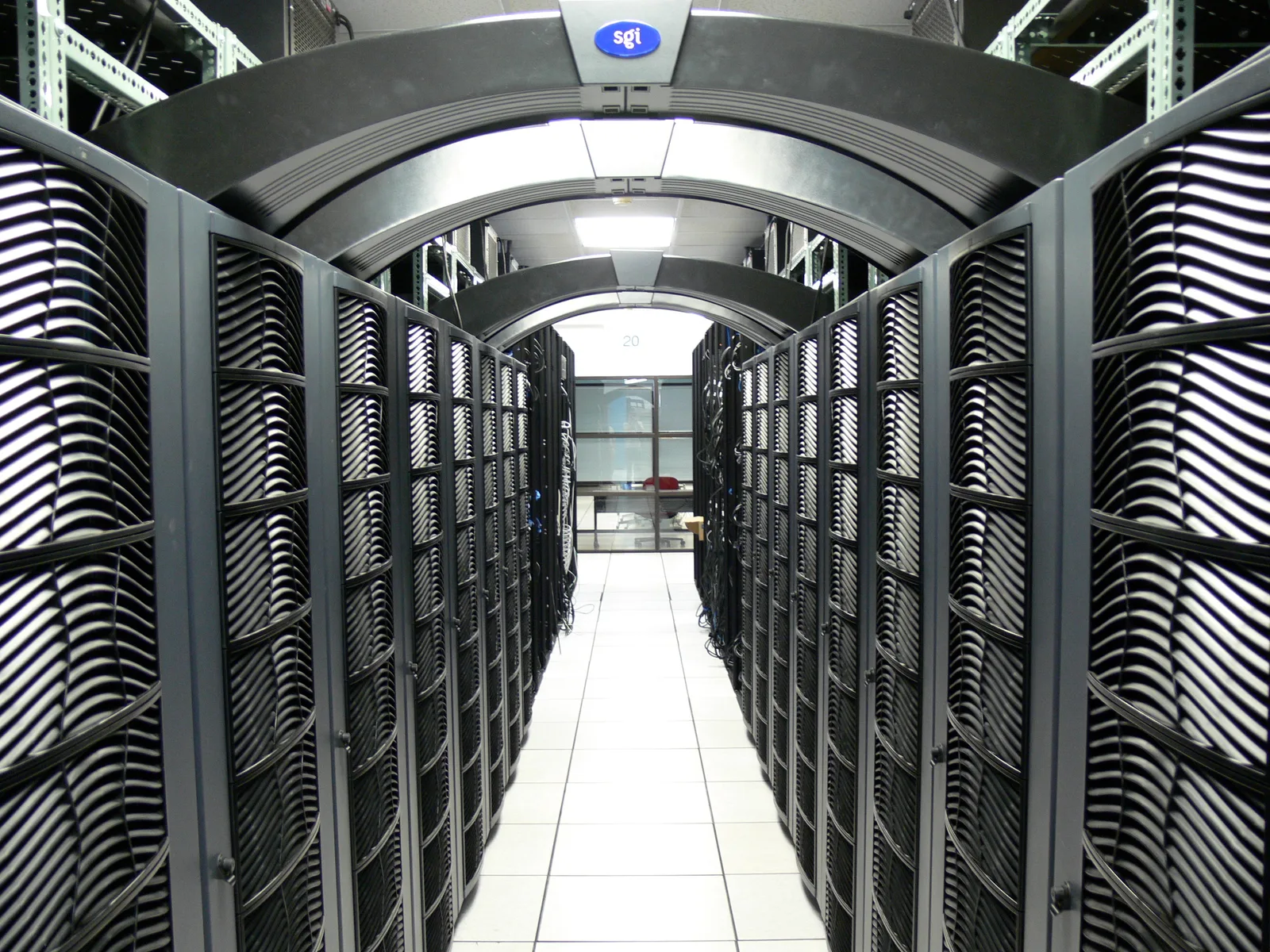 Long aisle between rows of black server racks with curved tops in a data centre