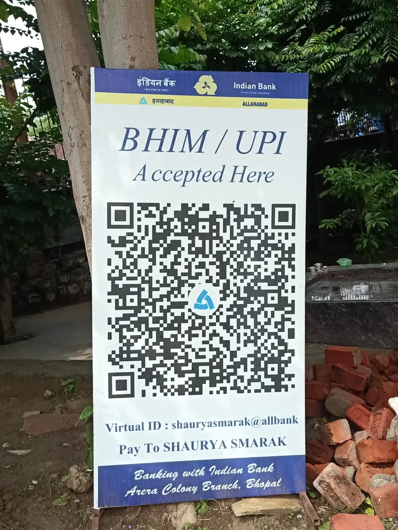 Standing sign with a large BHIM UPI QR code and Indian Bank branding accepting entrance fees at Shaurya Smarak in Bhopal