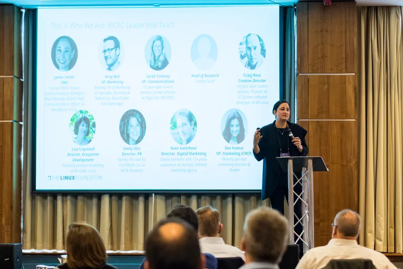 A speaker at a lectern presents a Linux Foundation slide to a seated audience at Open Source Summit Europe in Edinburgh in October 2018
