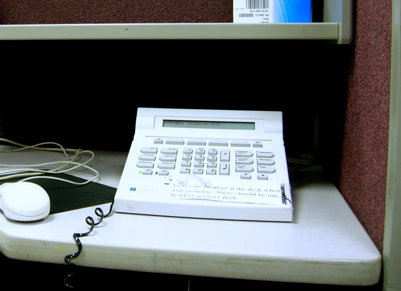 Call-centre telephone console and handset on a desk.