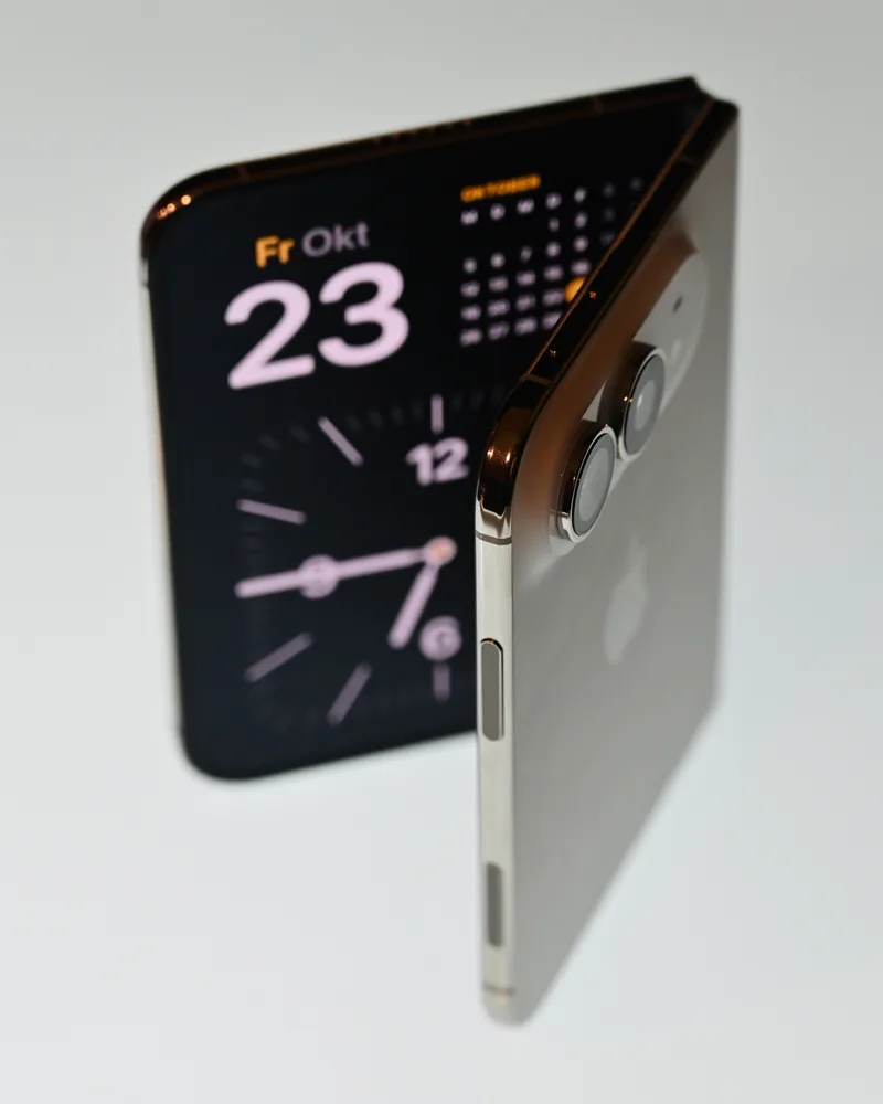 iPhone Duo standing partly folded, outer display showing the date and time.